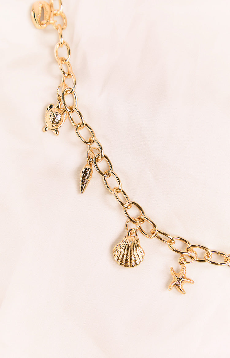 Close-up of the gold chain belt featuring a turtle, conch shell, scallop shell, and starfish charms