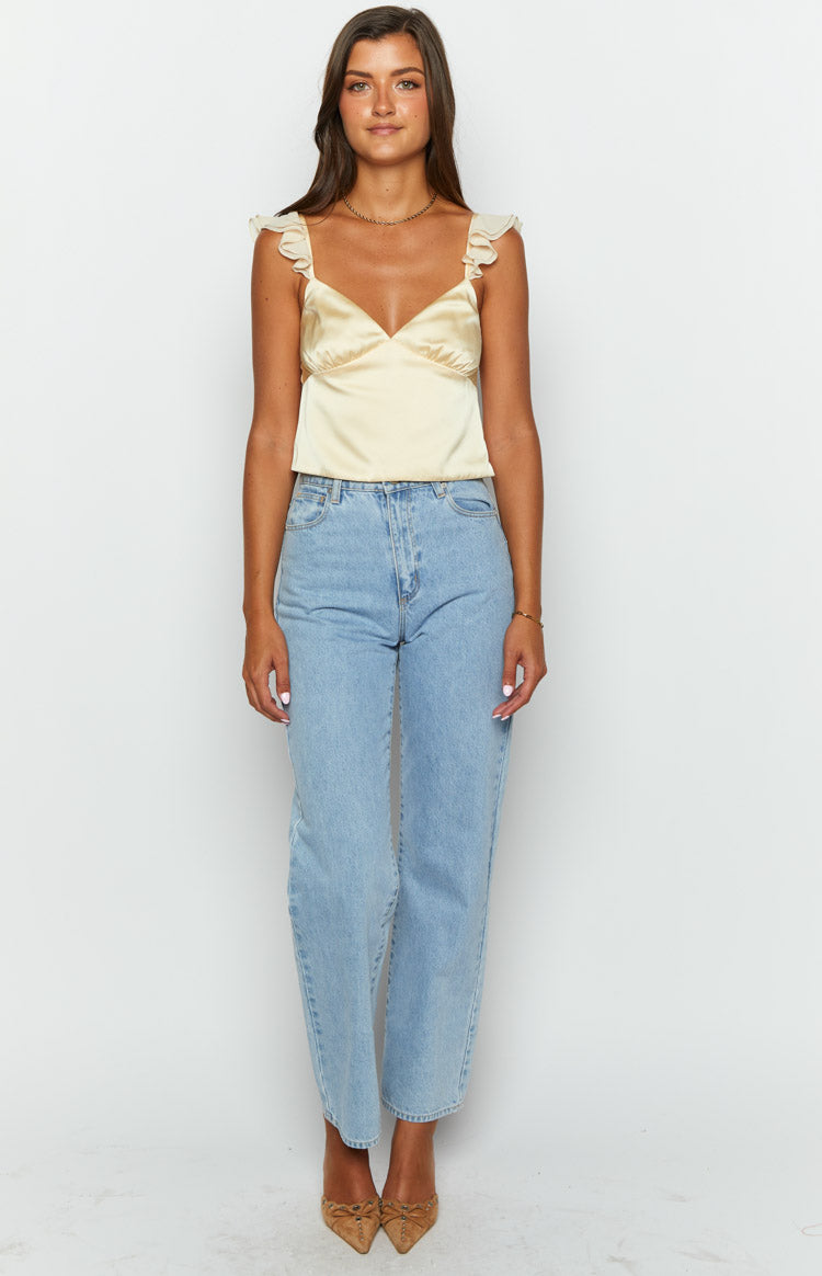 Front view of a pale yellow satin crop top with a V-neckline and ruffled shoulder straps