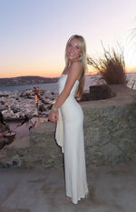 Side view of a cream strapless mesh maxi dress with a fitted silhouette and ruched side detail