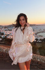 Iridescent pearl satin mini dress with a high ruffled neckline, tie detail, and voluminous long sleeves