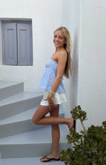 Side view of a light blue and white striped strapless top with a peplum hem and visible tie-back detail