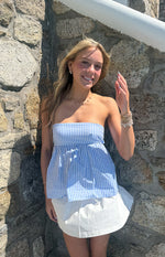 Front view of a light blue and white striped strapless top with a gathered peplum hem