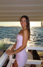Side view of a baby pink strapless bodycon mini dress with full side ruching and a high slit