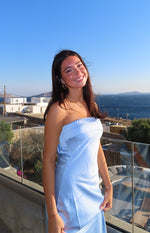 Side view of a light blue strapless satin maxi dress with a fitted bodice and horizontal seam details