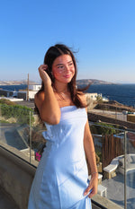 Side view of a light blue strapless maxi dress with a folded bust and a large bow detail on the hip
