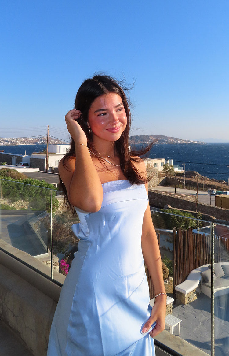Side view of a light blue strapless maxi dress with a folded bust and a large bow detail on the hip