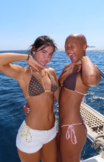Front view of a brown triangle bikini top with small white polka dots and thin yellow string ties