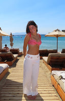 Front view of white wide-leg pants featuring delicate floral cutouts along the top waistband