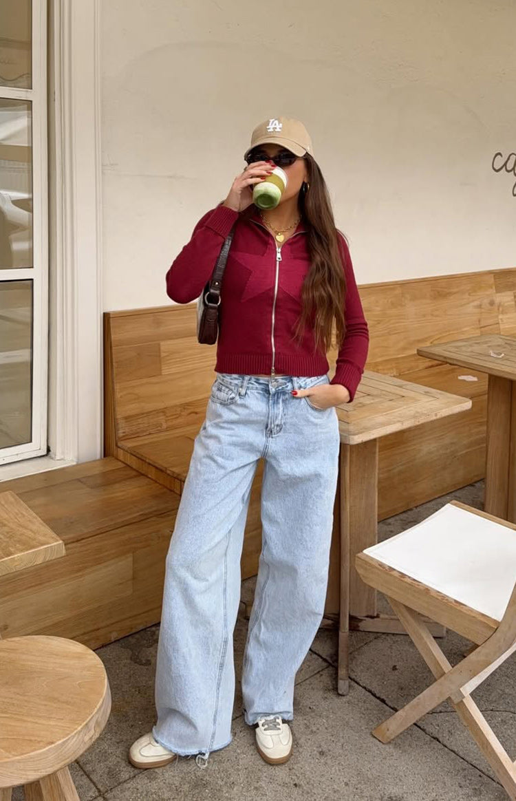 Burgundy cropped knit sweater with a full zip front, large star design on the chest, and ribbed hem