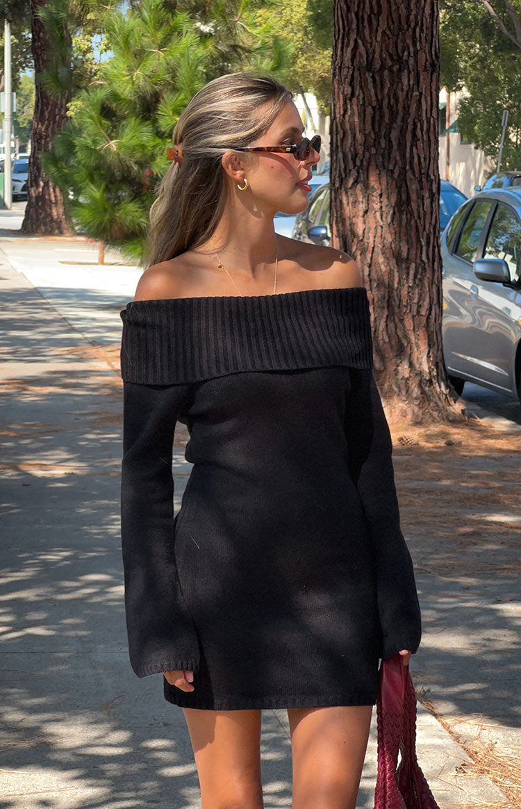 Side view of a black knit off-the-shoulder mini dress with a ribbed fold-over neckline and long sleeves