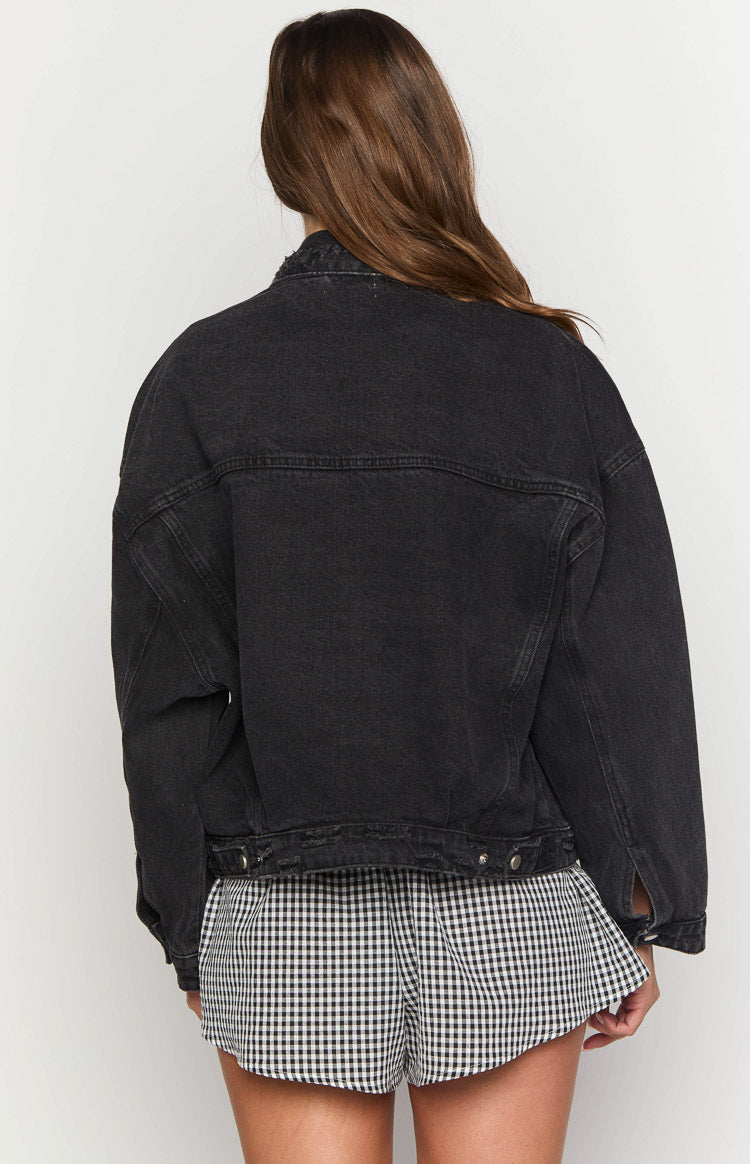 Rear view of a black oversized denim jacket with a back yoke and distressed hem
