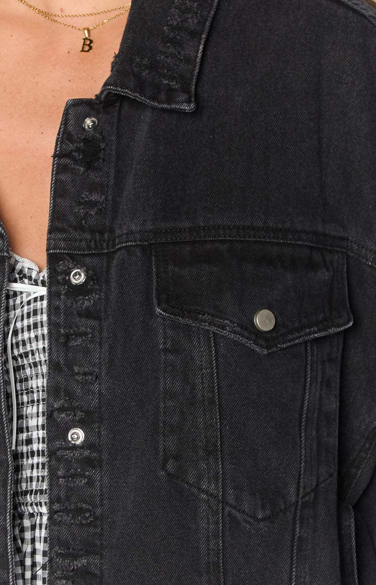 Distressed black denim jacket with chest pocket and silver button details