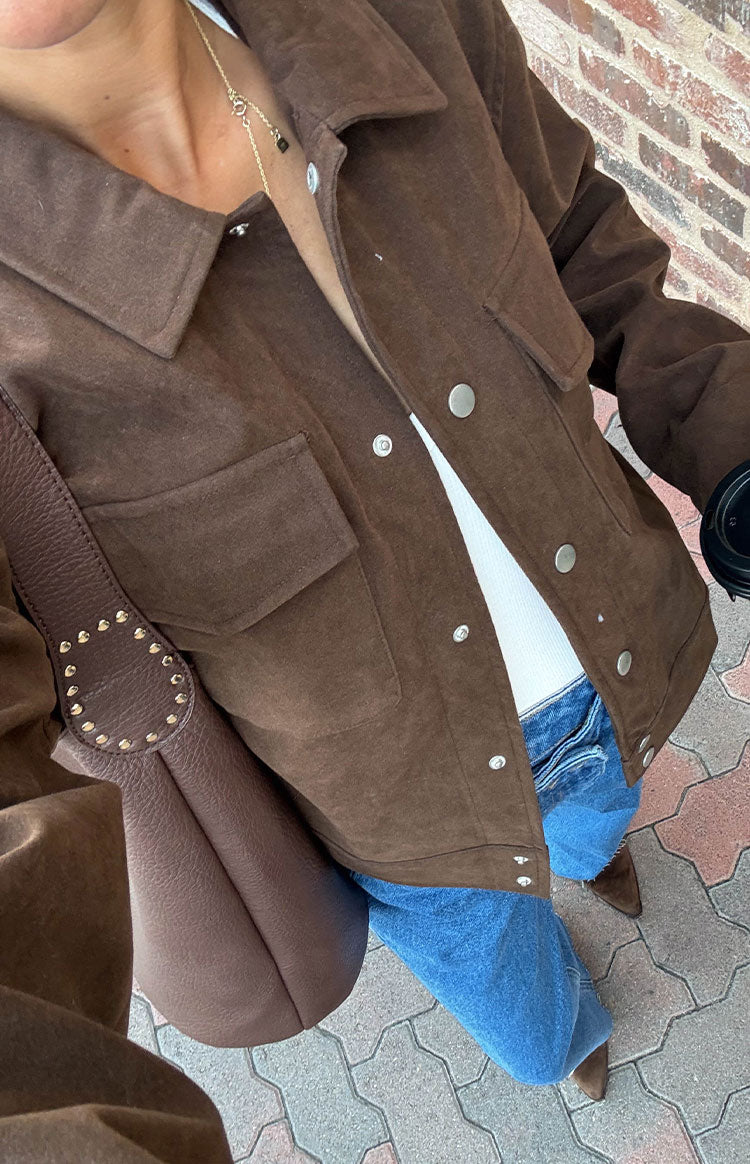 Overhead view of a chocolate brown suedette jacket showing the silver snap button front and chest pockets