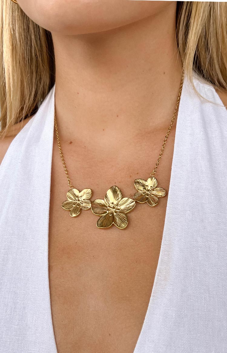 Close-up of the gold frangipani trio necklace showing the detailed textured petals and chain