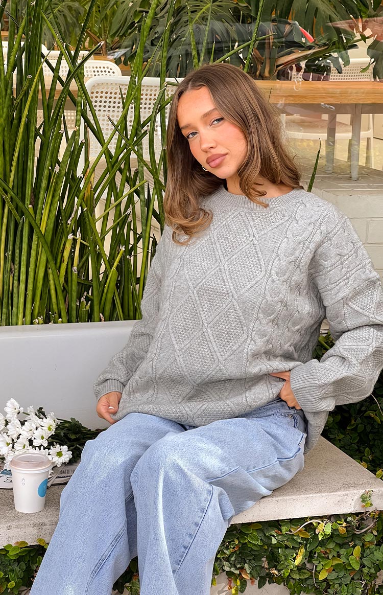 Close-up of the grey cable knit sweater, highlighting the diamond and braided patterns