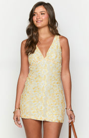 Front view of a yellow and white lace mini dress with a deep V-neck and fitted silhouette