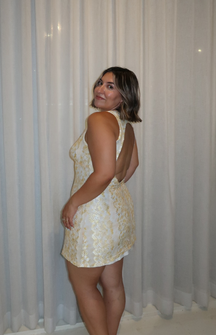 Side view of the yellow lace mini dress, highlighting its high neckline and deep open back