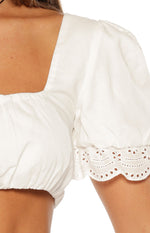 Close-up of the white broderie trim with scalloped edge on the puffed sleeve cuff and shirred hem of the crop top