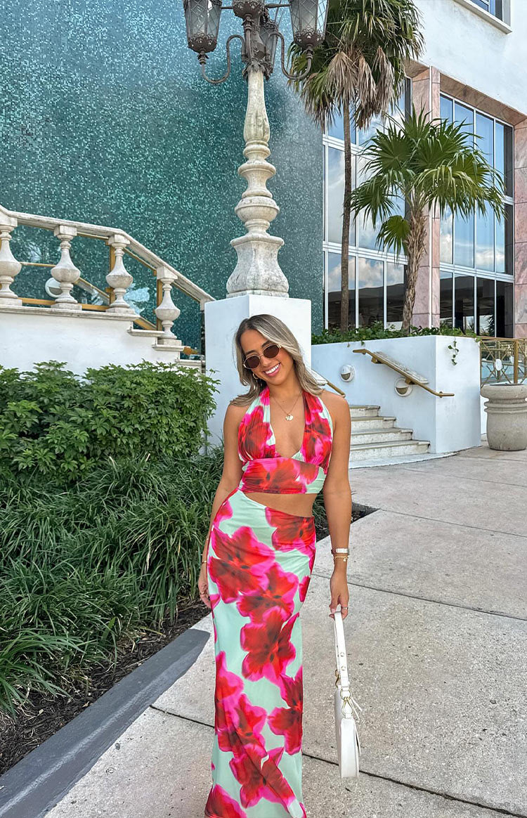 Full length view of a green floral print maxi dress with a halter neckline and waist cutouts