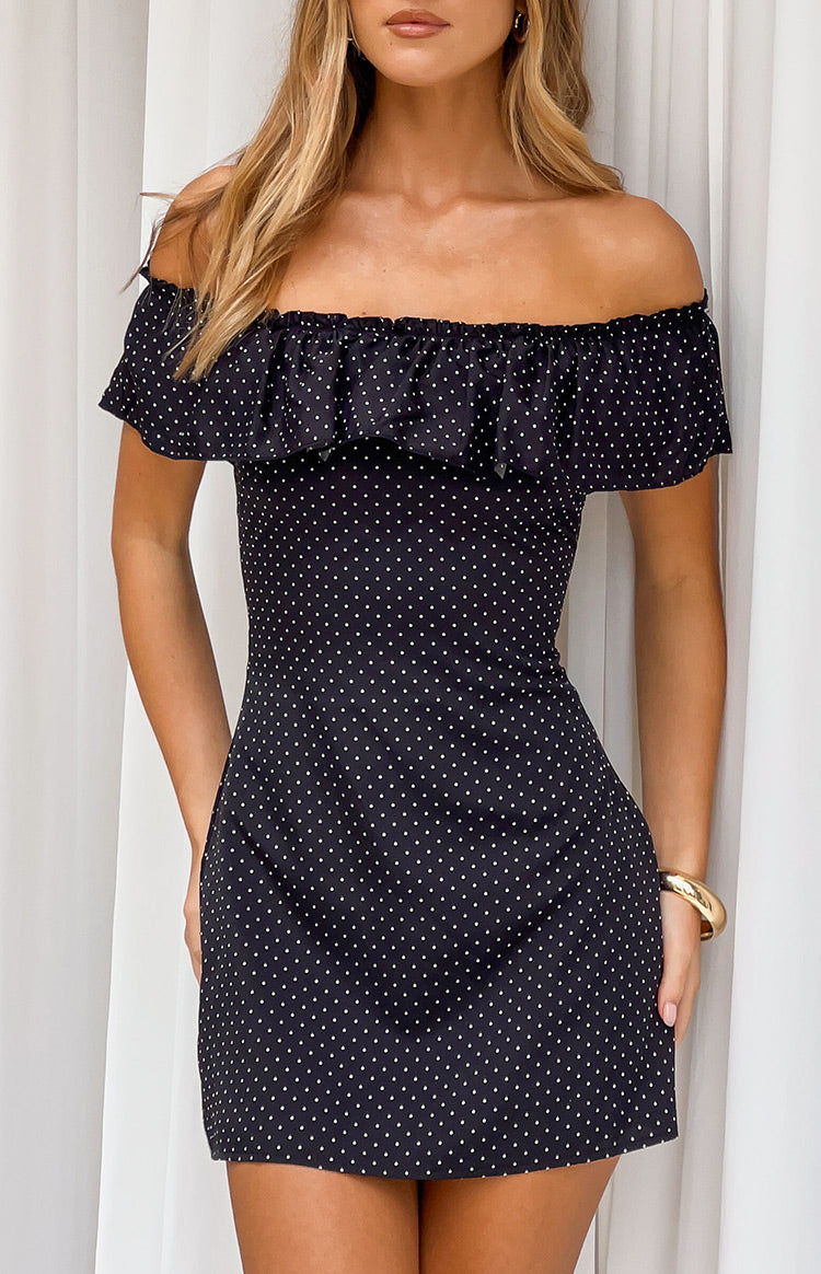 Black mini dress with white polka dots and a wide ruffled elasticated off-shoulder neckline
