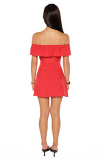 Rear view of a red polka dot off-shoulder mini dress with a ruffled neckline and fitted waist