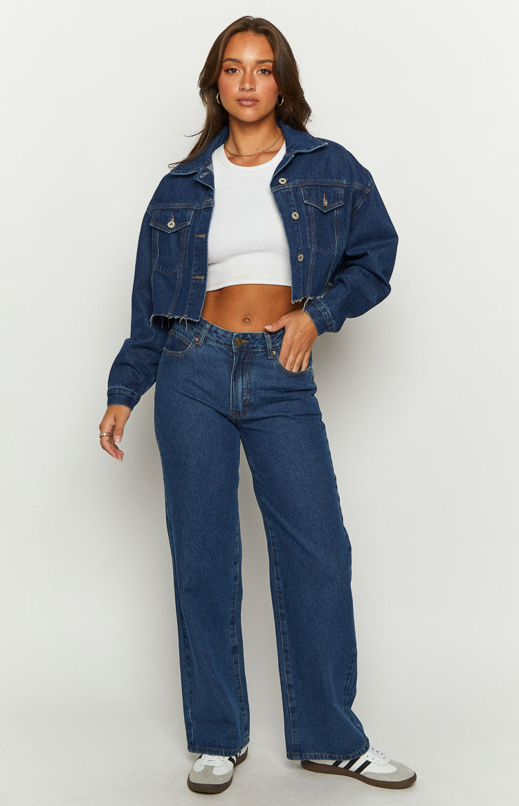 Front view of a dark wash denim cropped jacket with a raw frayed hem and relaxed fit