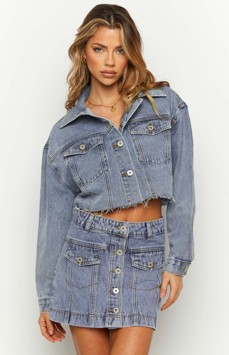 Mid wash denim cropped jacket with a relaxed fit, frayed hem, and button-front