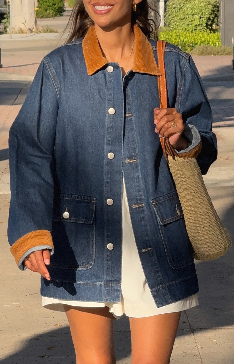 Front view of an oversized mid-wash denim jacket with tan corduroy collar and cuffs, white buttons, and patch pockets