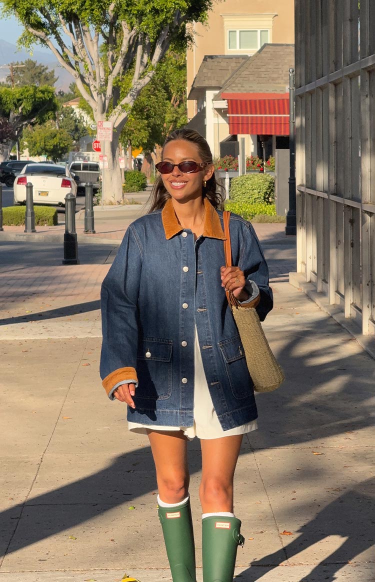 Front view of an oversized mid-wash denim jacket with a tan corduroy collar and cuffs, featuring large patch pockets and white buttons