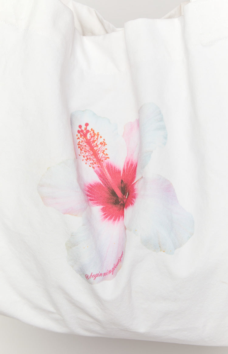 Close-up of a large pink and white hibiscus flower print with red stamen detail on a white tote bag