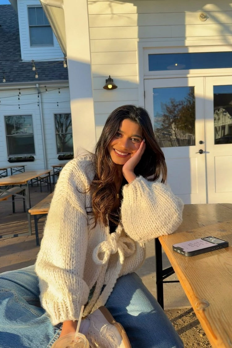 Close-up of a cream chunky knit cardigan with a tie-up front closure and wide ribbed cuffs