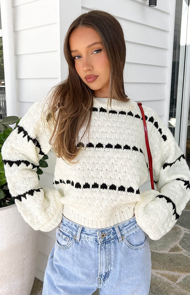 Close-up of the cream knit sweater with black heart stripe pattern and voluminous sleeves