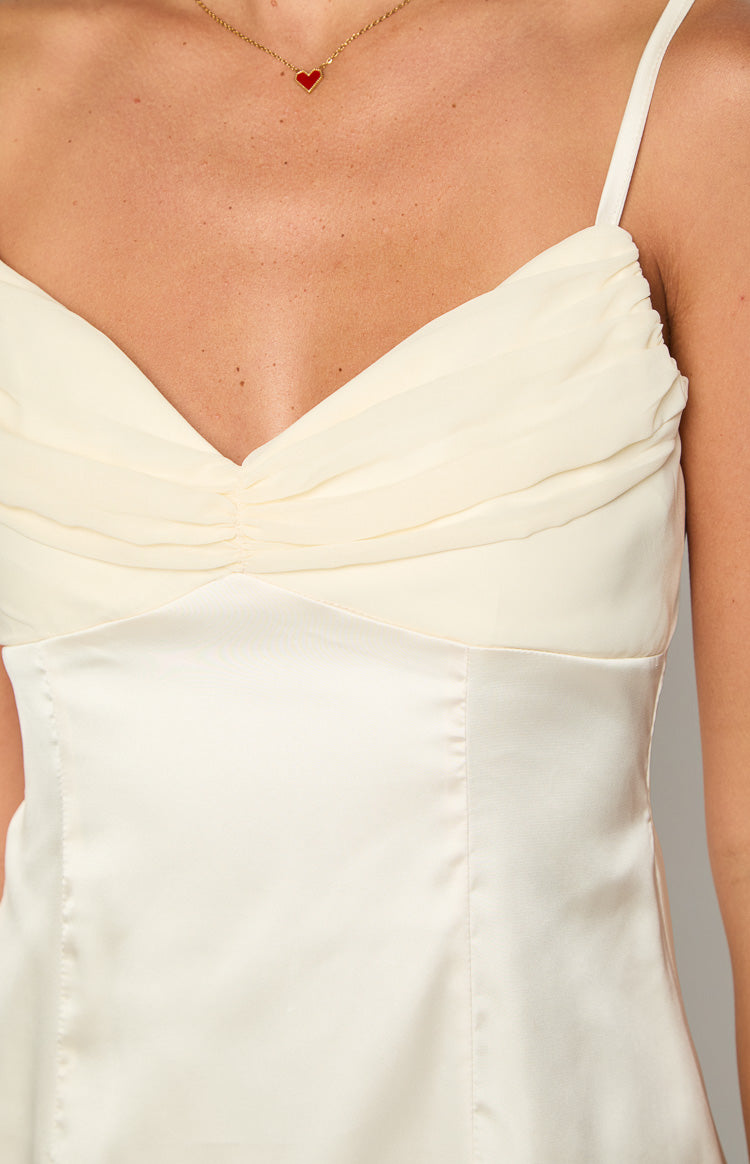Close-up of the cream mini dress showing the ruched sheer bust and smooth satin bodice with spaghetti strap