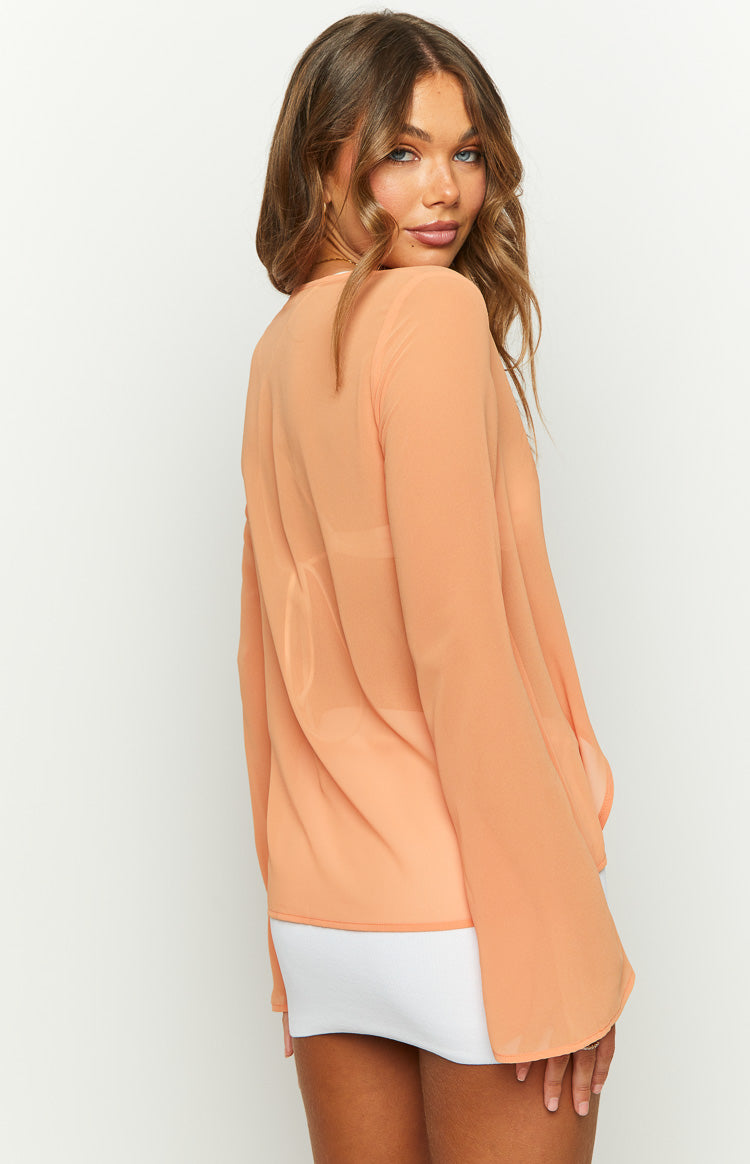 Side view of the sheer orange chiffon long sleeve top showing its loose fit and flowy sleeves