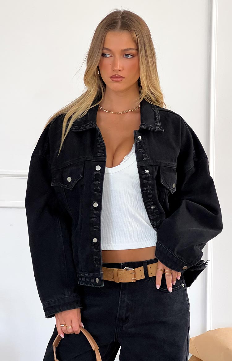 Front view of an oversized black denim jacket with distressed collar and button-front closure