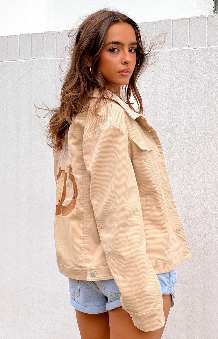 Rear view of a cream corduroy western jacket with a large brown horseshoe embroidery on the back