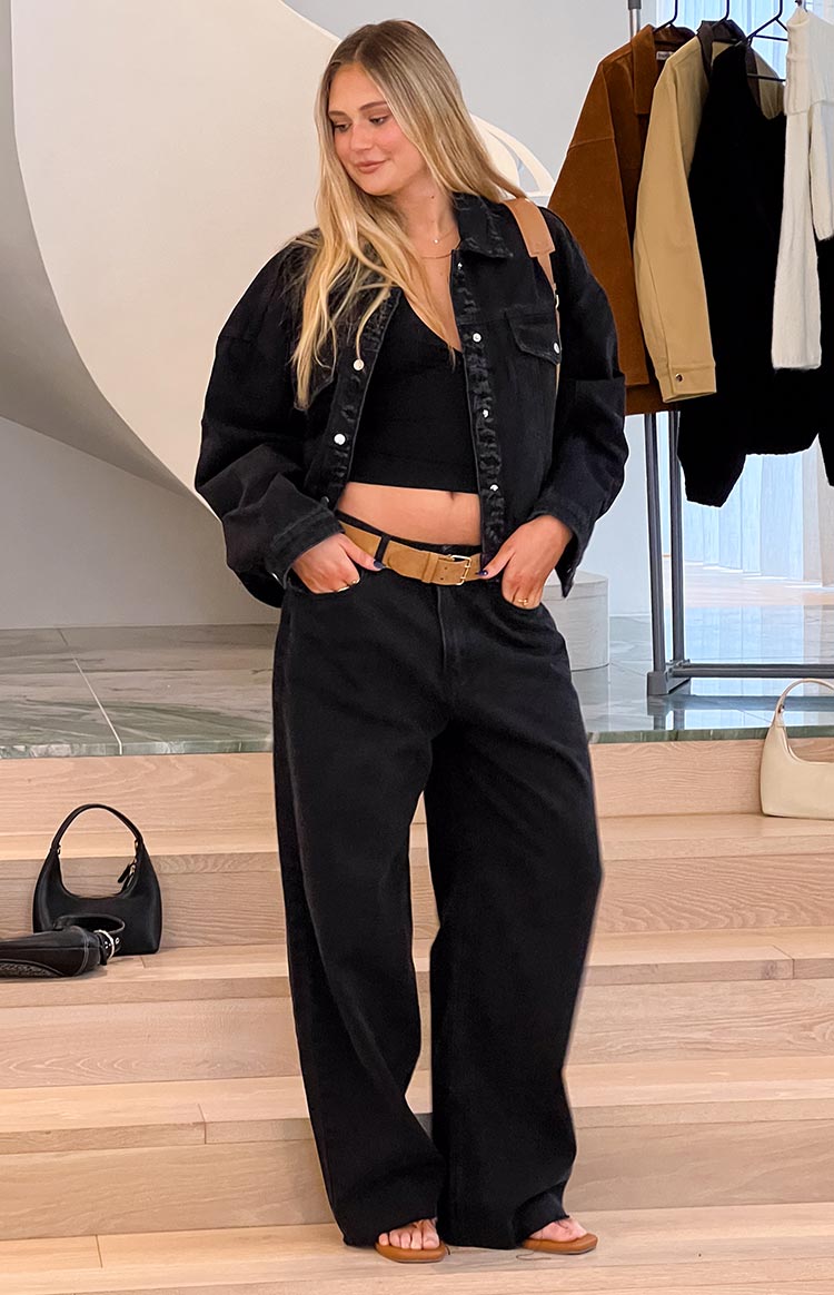 Black oversized denim jacket with silver buttons, worn open to show its relaxed silhouette and chest pockets