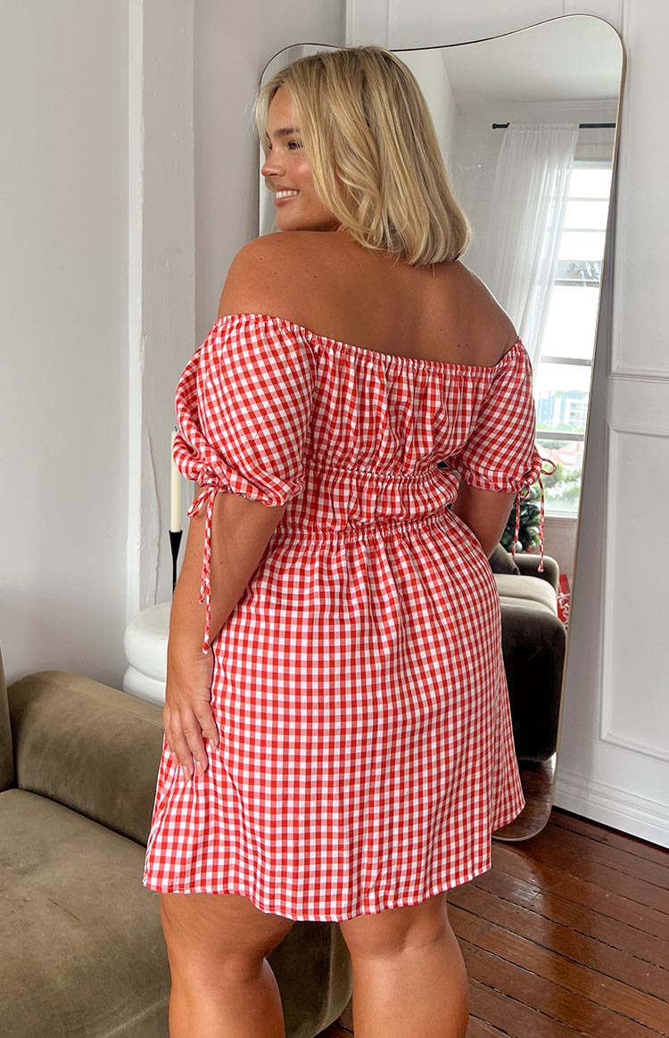 Rear view of a red gingham mini dress with an off-shoulder neckline, shirred waist, and puff sleeves with ties