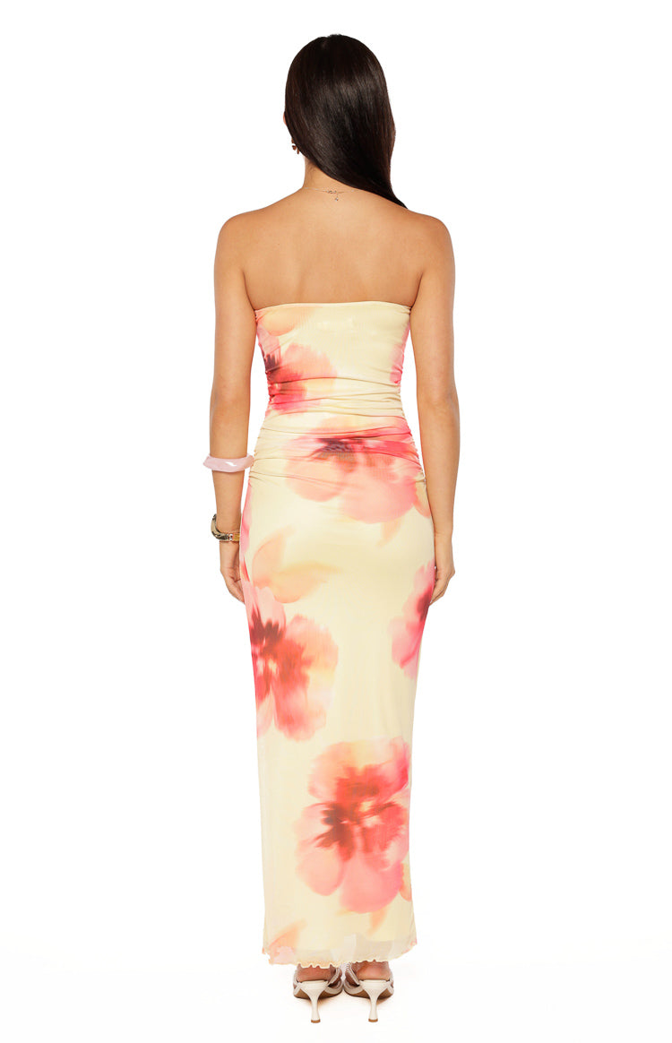 Rear view of a yellow and pink floral print strapless maxi dress with a fitted silhouette and sheer hem