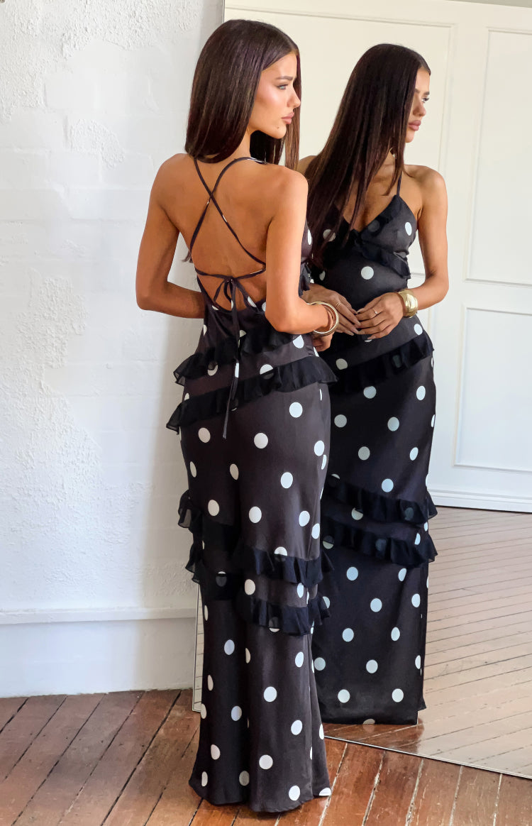 Rear view of a black polka dot maxi dress with criss-cross tie-back straps and tiered ruffles