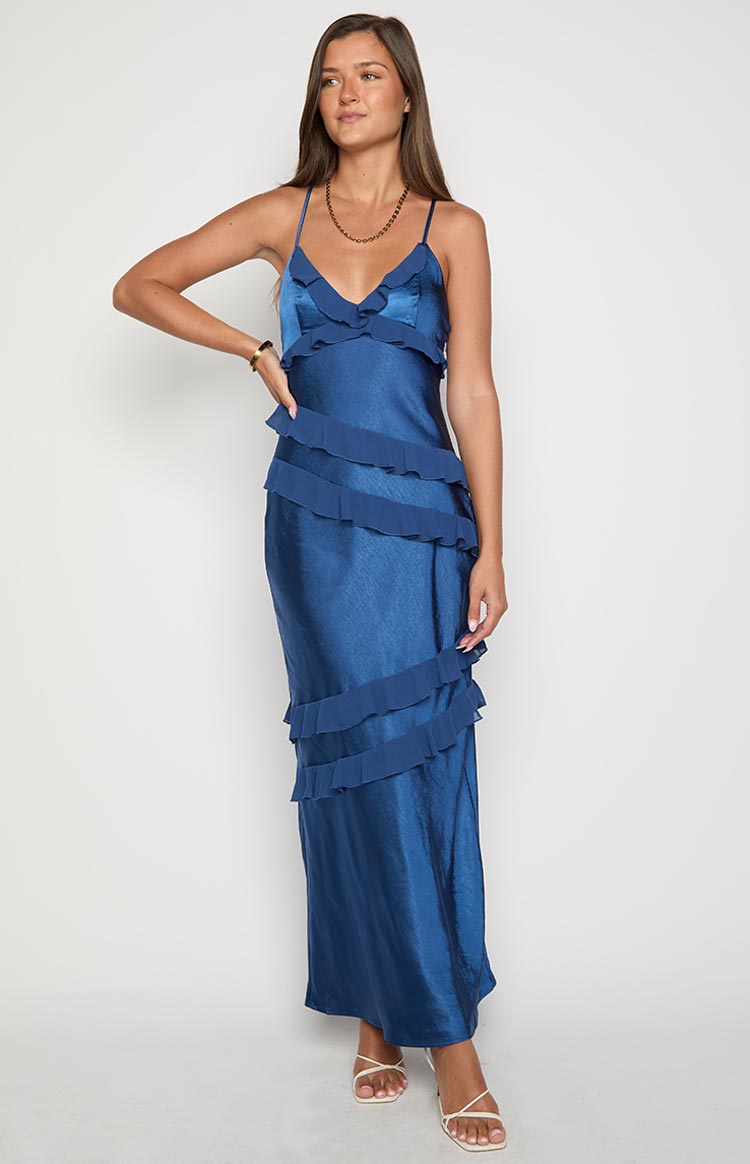 Navy satin maxi dress with V-neck, thin straps, and tiered diagonal ruffles down the front