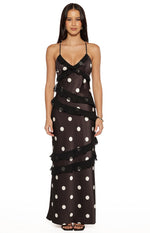 Front view of a black polka dot maxi dress with a V-neckline, thin spaghetti straps, and tiered ruffles