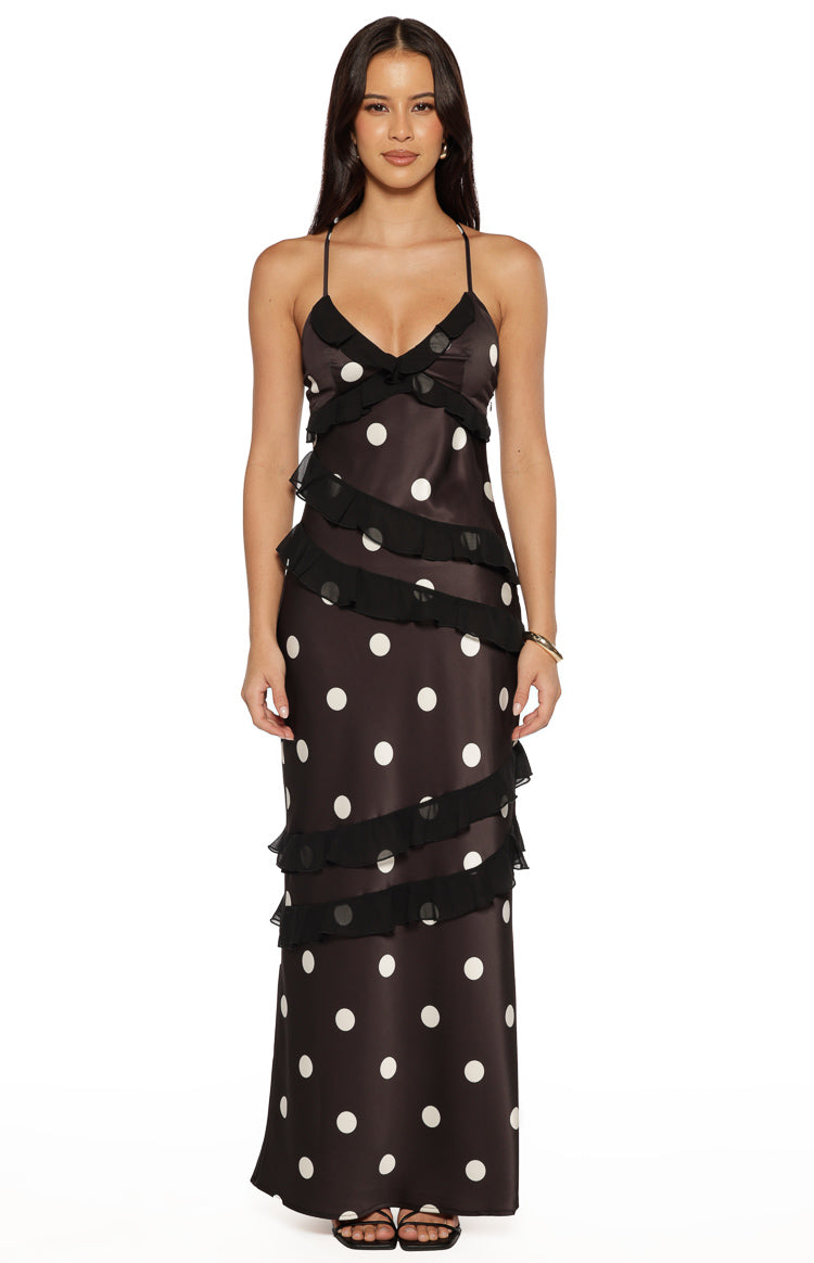 Front view of a black polka dot maxi dress with a V-neckline, thin spaghetti straps, and tiered ruffles