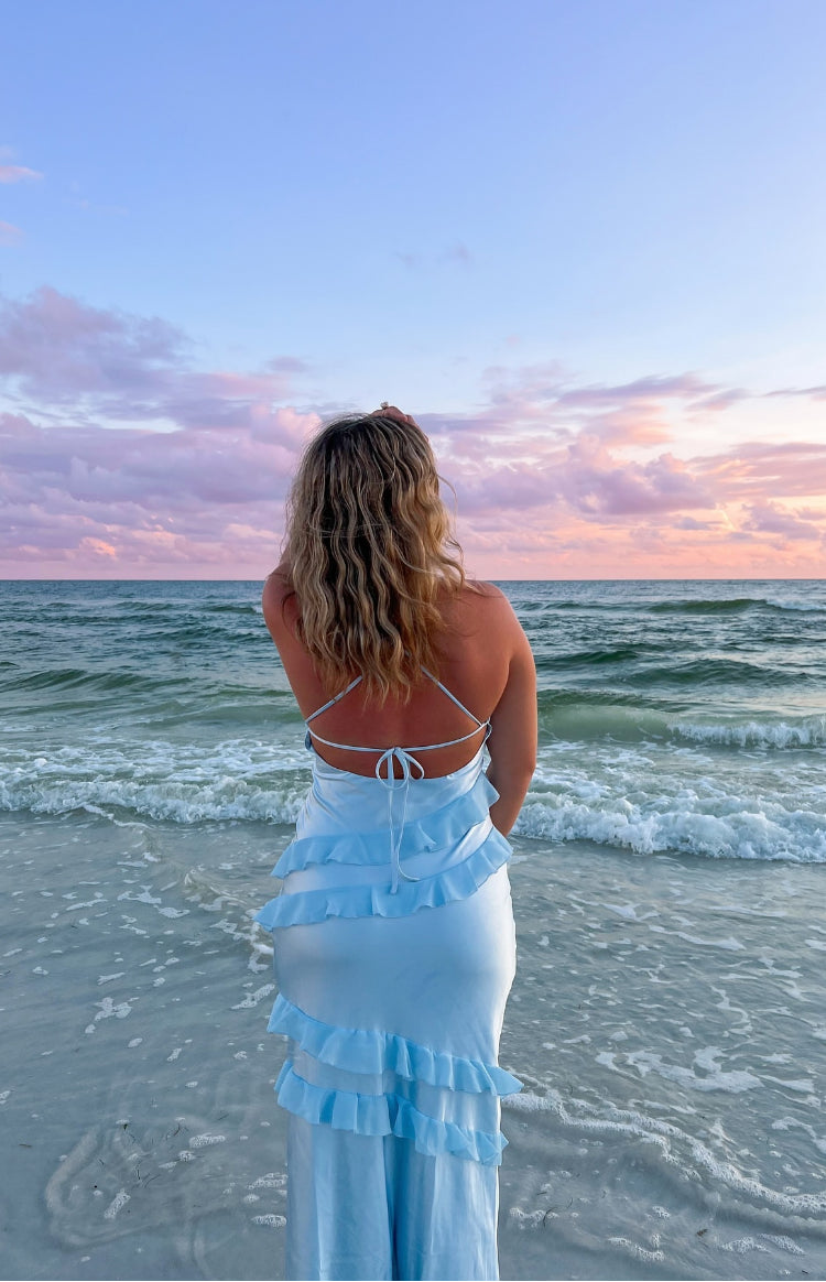 Rear view of a light blue maxi dress with criss-cross back straps, tie detail, and tiered ruffles