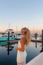 Side view of a white crochet maxi skirt with a fitted silhouette and openwork floral pattern at the hem