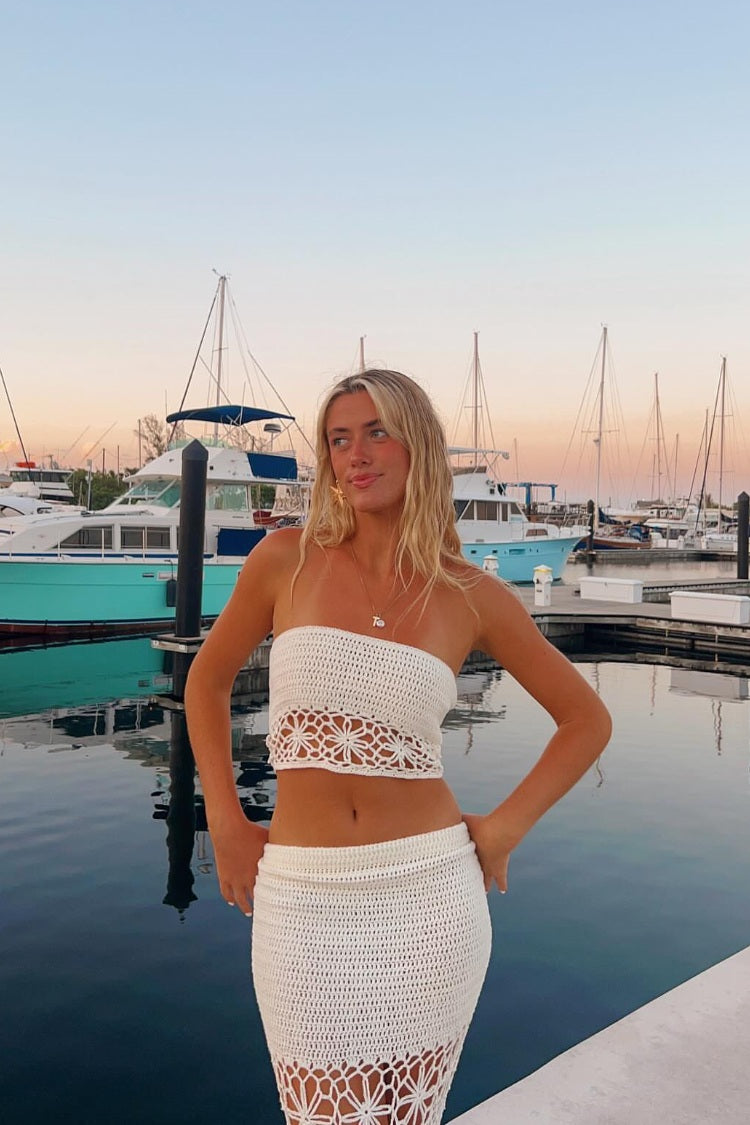 White crochet high-waisted maxi skirt with a fitted silhouette and floral cutout pattern at the hem