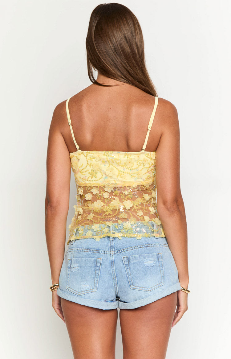 Rear view of a yellow sequin top with thin spaghetti straps and floral appliques