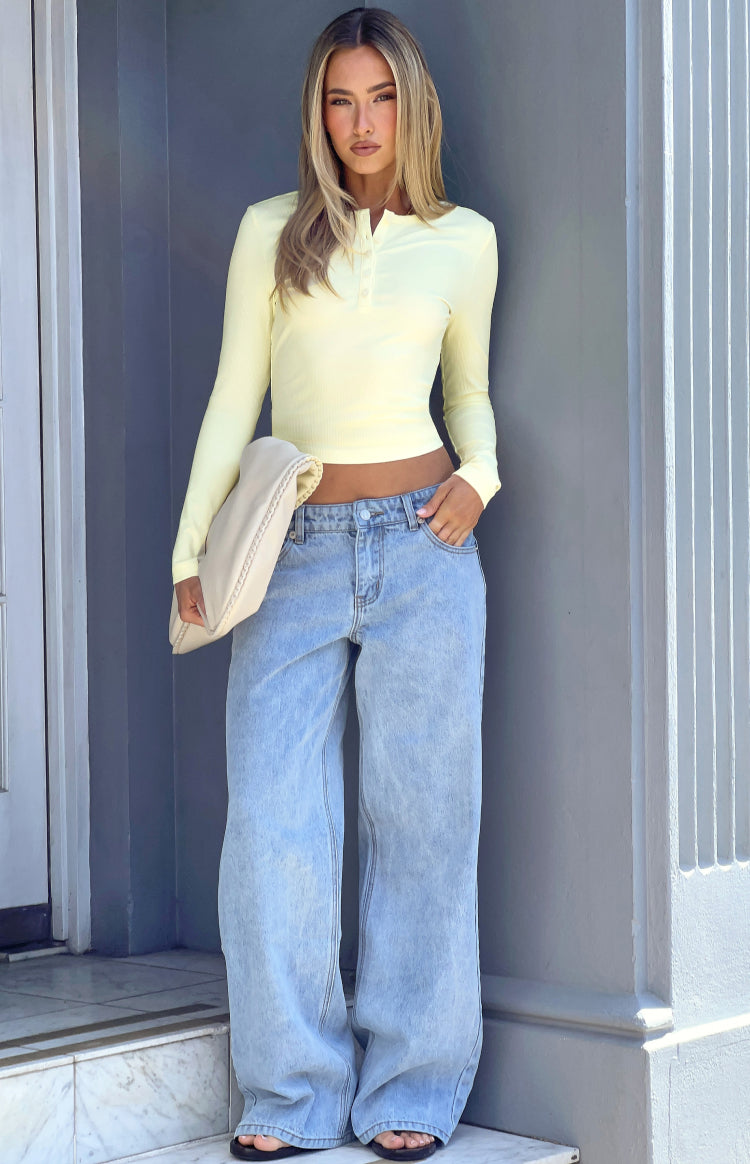 Pale yellow ribbed knit long sleeve top with a henley button placket and cropped hem