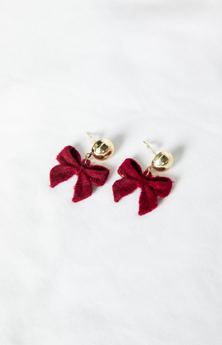 Pair of red velvet bow earrings with gold dome studs, showing the velvet texture