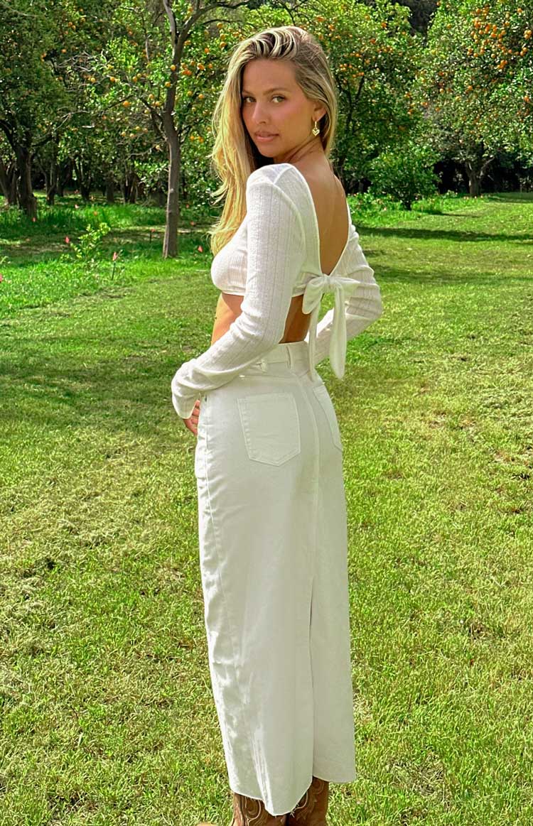 Side view of a white denim midi skirt with back pockets and a rear hem slit